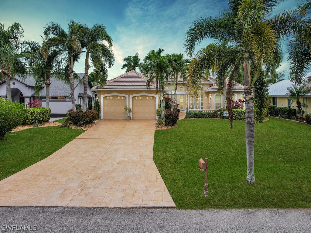 front view of house with a yard and palm trees