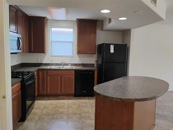 a kitchen with granite countertop wooden cabinets and a stove top oven