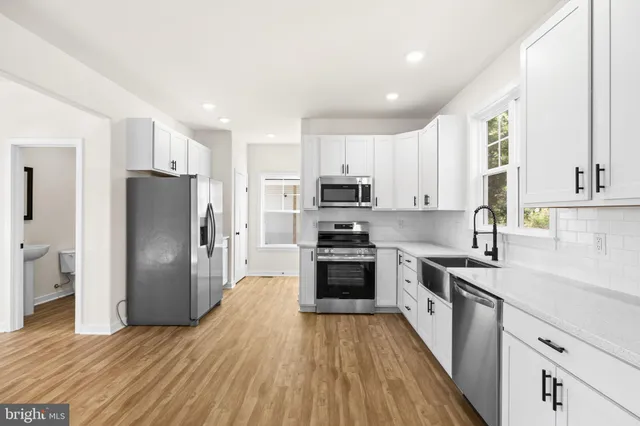 a kitchen with a refrigerator a stove top oven and wooden floor
