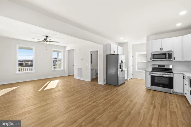 a view of a kitchen with a sink stove cabinets and empty room