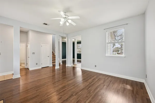 an empty room with wooden floor fan and windows