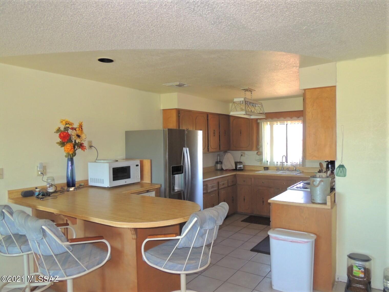 3454 East Fawn Ranch Road Pearce, AZ 85625 - Photo 16 of 49 a kitchen with refrigerator and chairs