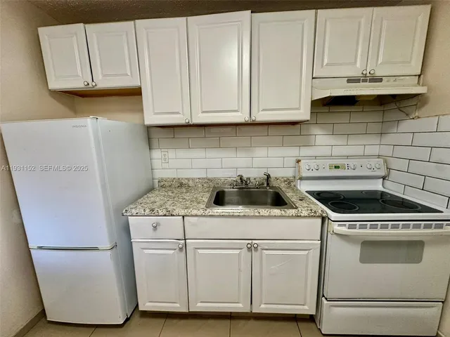 a kitchen with granite countertop white cabinets and white appliances