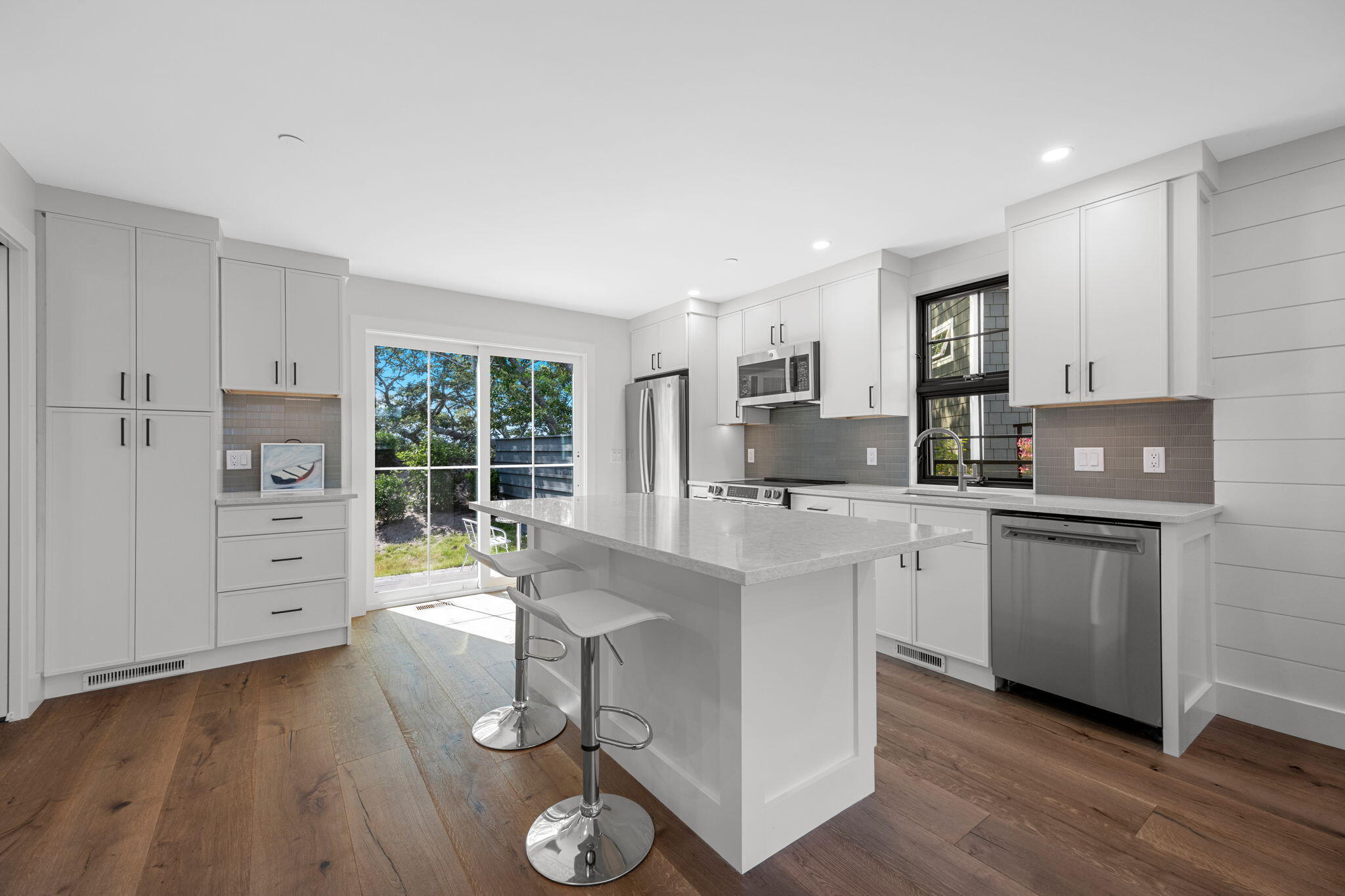 50 Nelson Avenue, Unit 8 Provincetown, MA 02657 - Photo 3 of 21 a kitchen with stainless steel appliances granite countertop a stove a sink a refrigerator and white cabinets with wooden floor