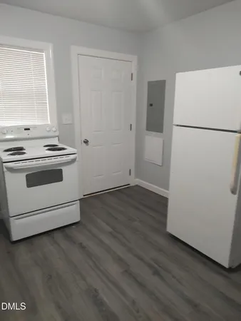 an empty room with wooden floor and a stove top oven