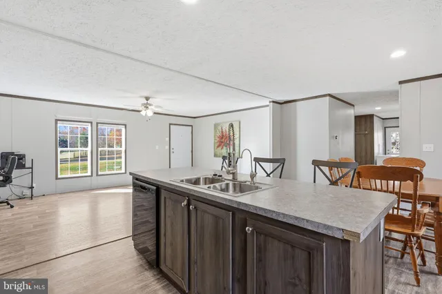 a kitchen with a sink a counter top space and living room view