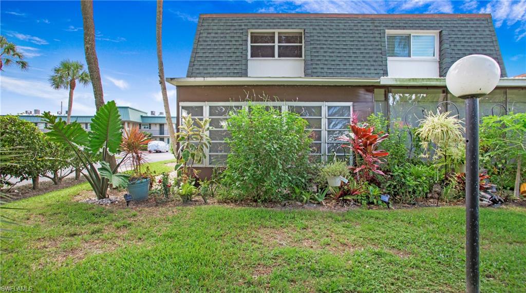 600 Valley Stream Drive, Unit C1 Naples, FL 34113 - Photo 27 of 44 Back of property with mansard roof, a lawn, and a shingled roof