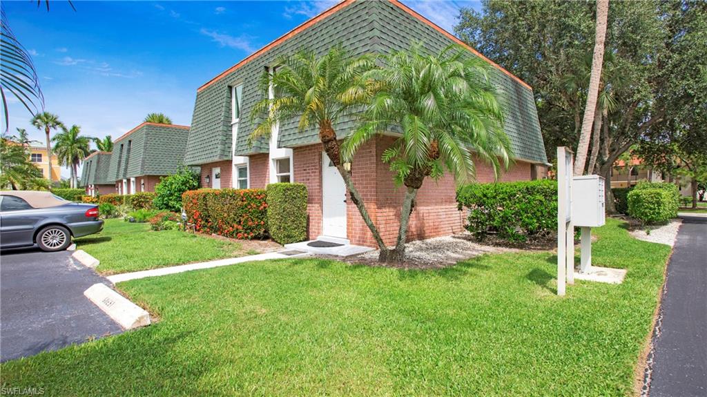 600 Valley Stream Drive, Unit C1 Naples, FL 34113 - Photo 31 of 44 View of side of property with mansard roof, brick siding, and a yard