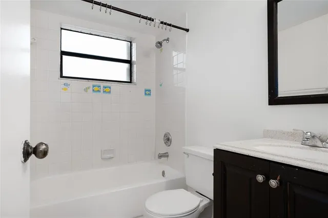 a bathroom with a sink vanity mirror bathtub and toilet