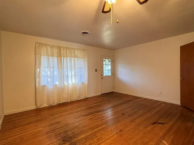 an empty room with wooden floor cabinet and windows