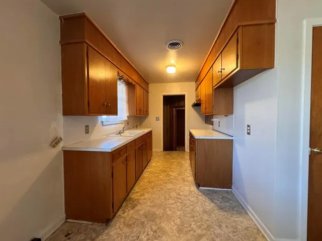a large kitchen with a sink and dishwasher a oven with wooden cabinets