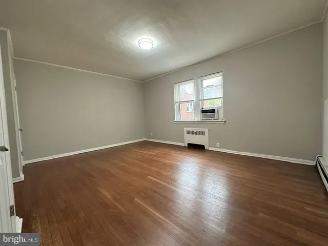 an empty room with wooden floor & windows