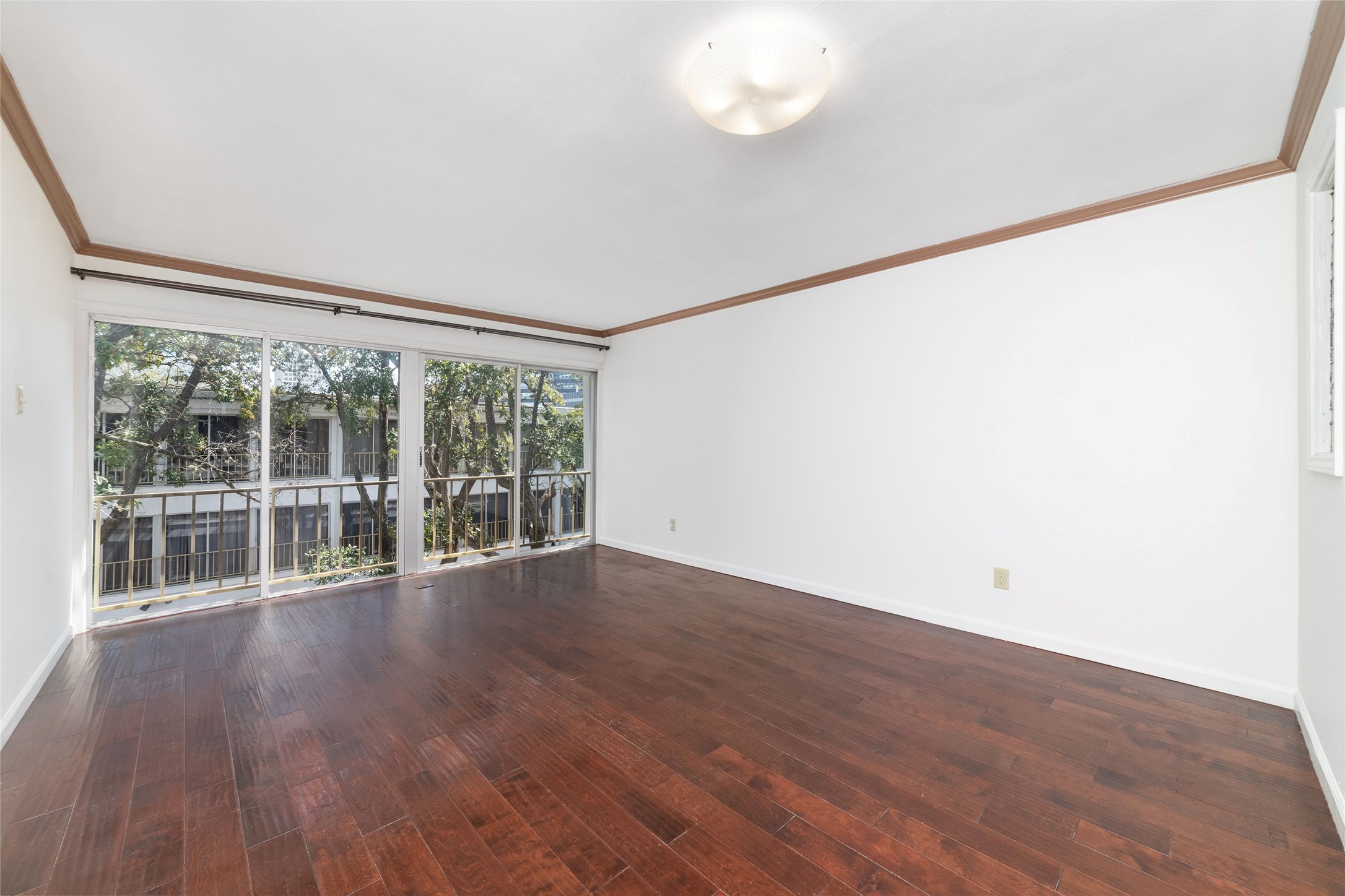 5050 Ambassador Way, Unit 309 Houston, TX 77056 - Photo 28 of 42 a view of an empty room with wooden floor and a window