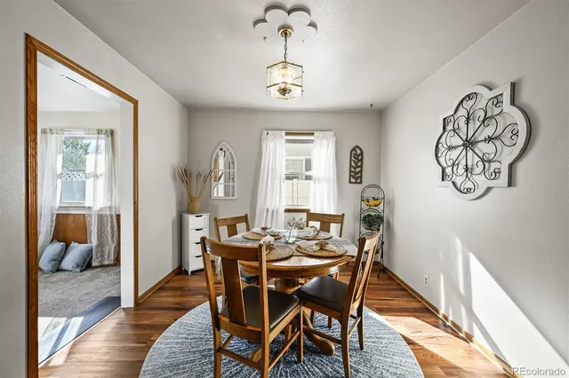 a dining room with wooden floor a chandelier a wooden table and chairs