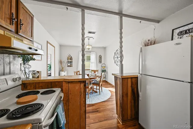 a kitchen with a refrigerator a stove and a dining table next to a window