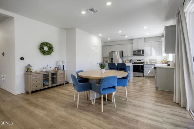 a kitchen with stainless steel appliances a dining table chairs and wooden floor