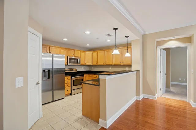 a kitchen with stainless steel appliances kitchen island granite countertop a refrigerator and a sink