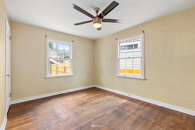 an empty room with windows and ceiling fan