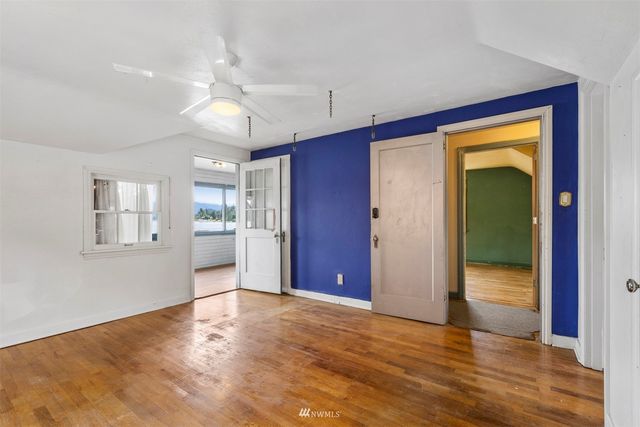 a view of an empty room with window and wooden floor