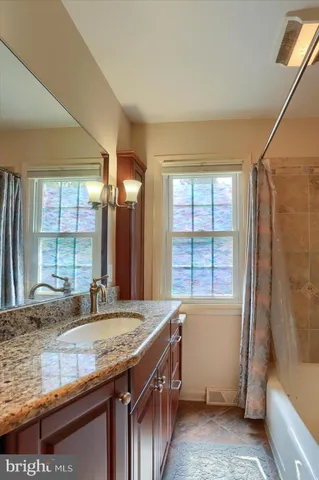 a bathroom with a granite countertop sink and a bathtub