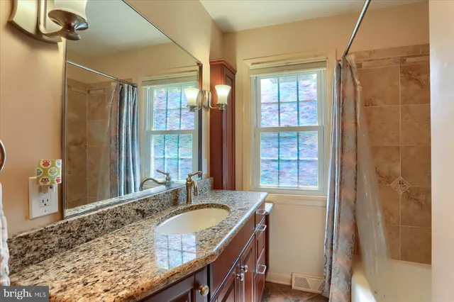 a bathroom with a granite countertop sink a mirror and a shower