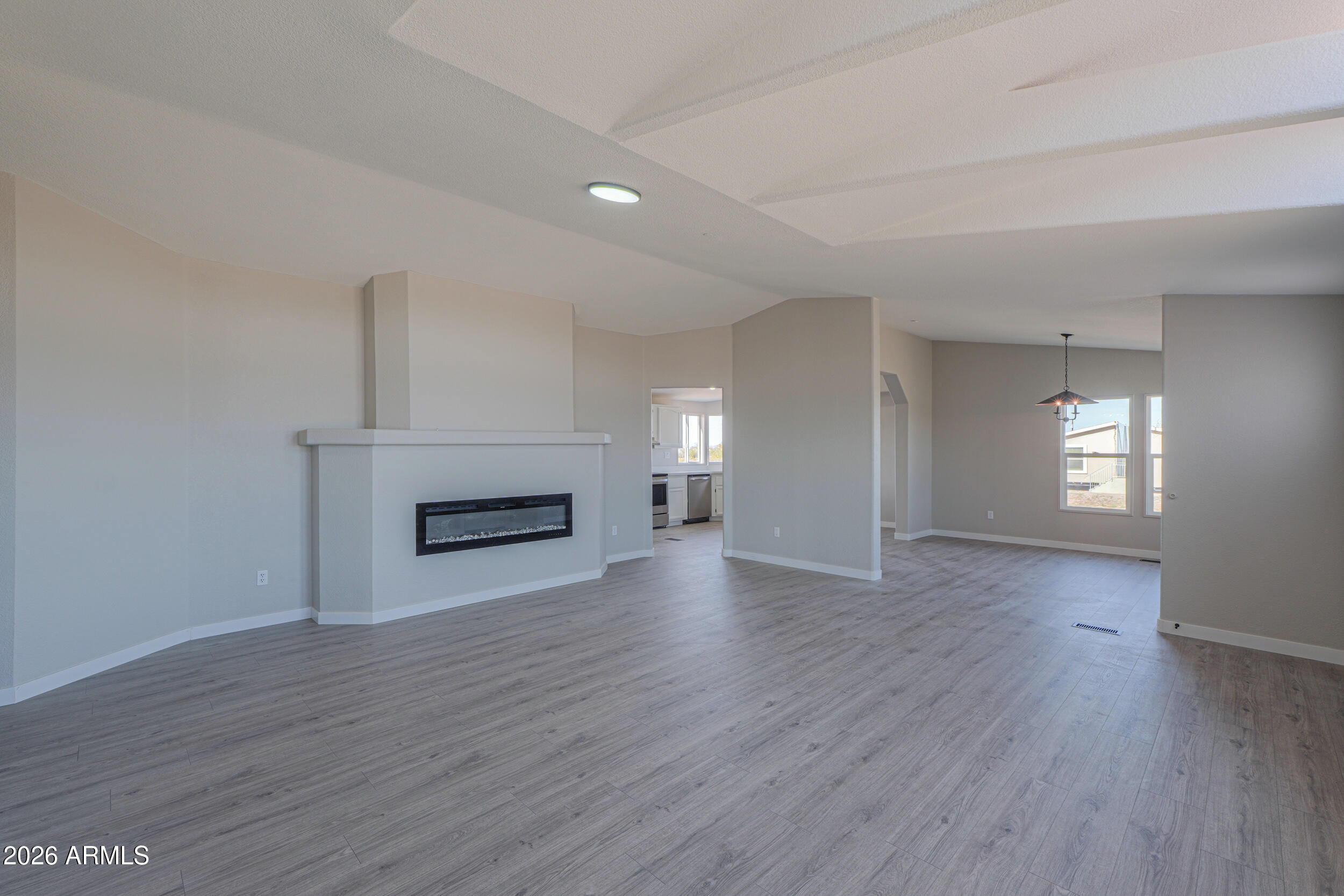 161 North Pueblo Road Maricopa, AZ 85139 - Photo 11 of 76 an empty room with wooden floor fireplace and windows