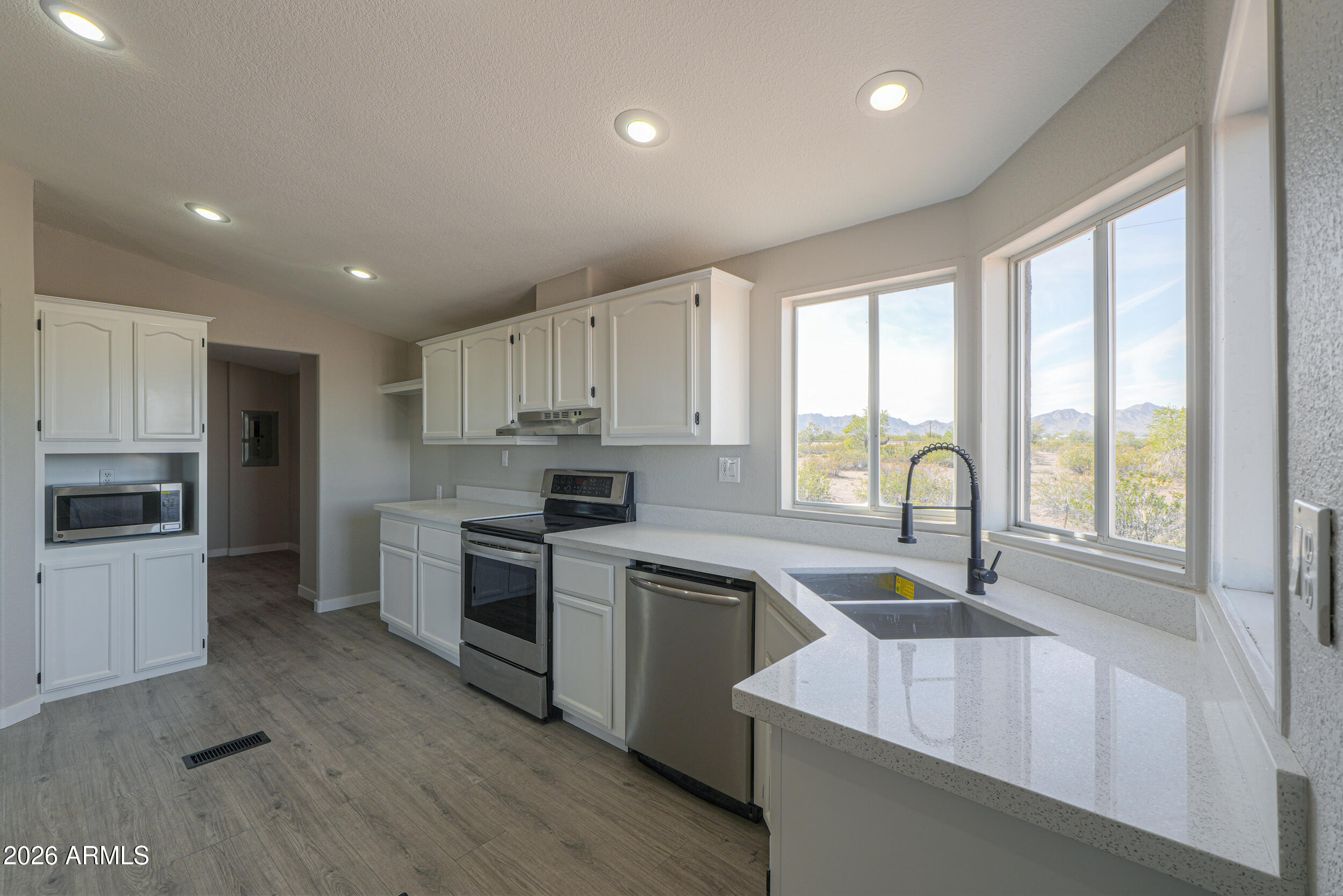 161 North Pueblo Road Maricopa, AZ 85139 - Photo 21 of 76 a kitchen with stainless steel appliances granite countertop a sink a stove top oven a refrigerator with grey cabinets and wooden floor