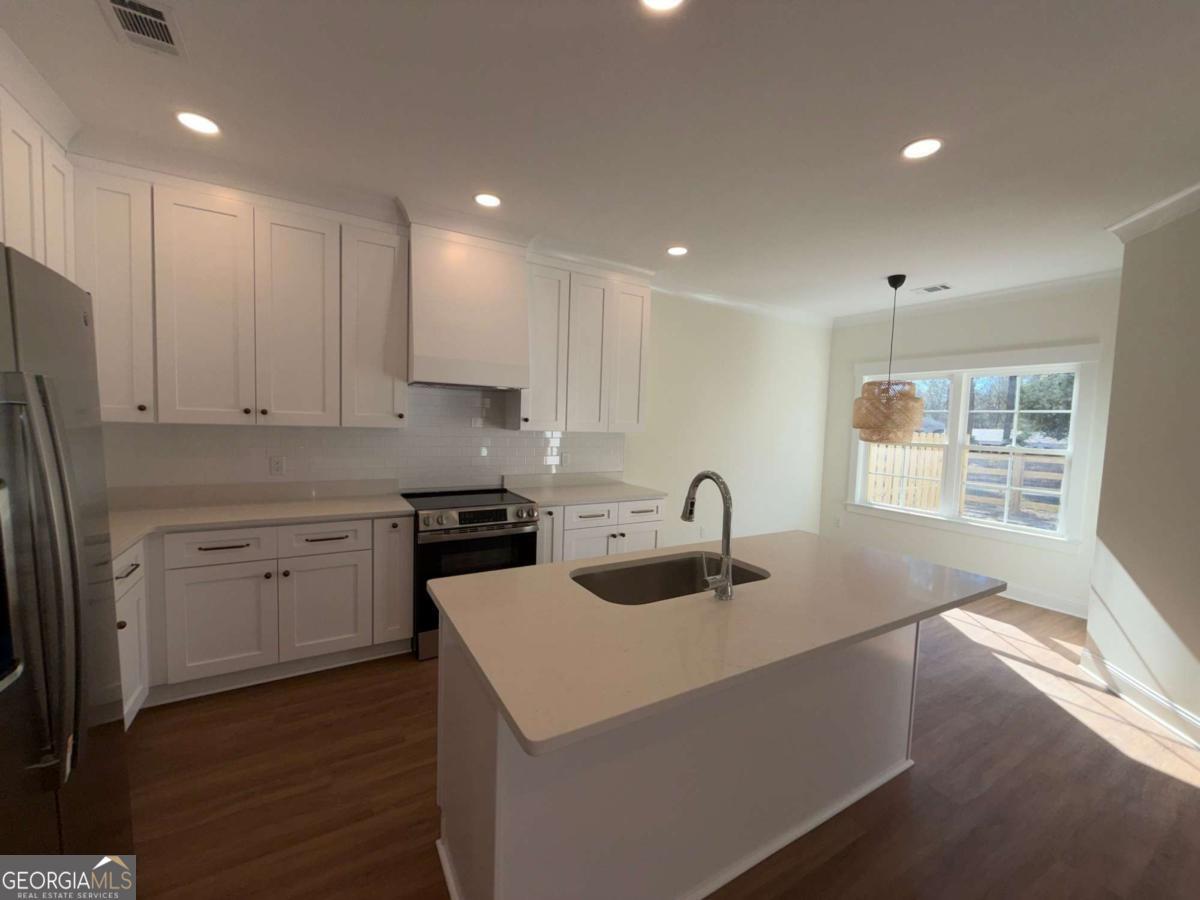 350 Rucker Lane, Unit AB Statesboro, GA 30458 - Photo 5 of 20 a kitchen with kitchen island sink stove refrigerator and cabinets