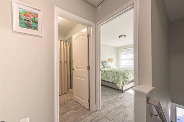 a view of a hallway and a livingroom with wooden floor and a bedroom