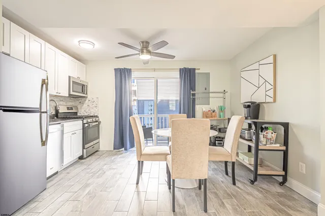 a kitchen with stainless steel appliances a dining table chairs refrigerator and sink