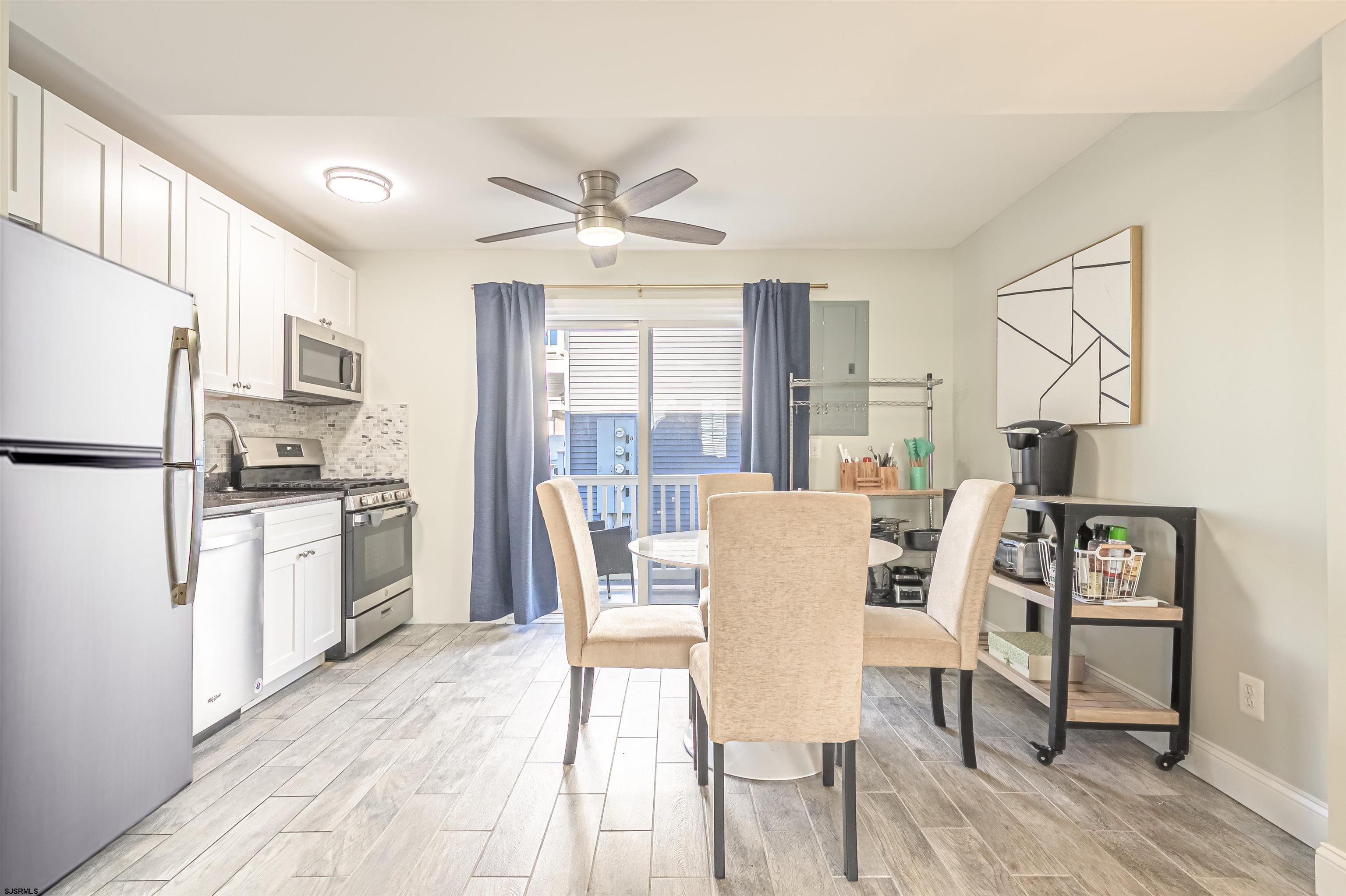 229 10th Street North, Unit 2 Brigantine, NJ 08203 - Photo 6 of 27 a kitchen with stainless steel appliances a dining table chairs refrigerator and sink