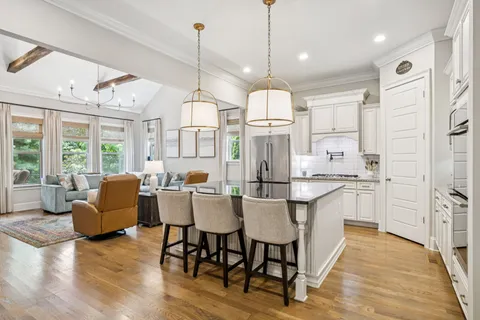 a kitchen with stainless steel appliances a dining table chairs sink and cabinets