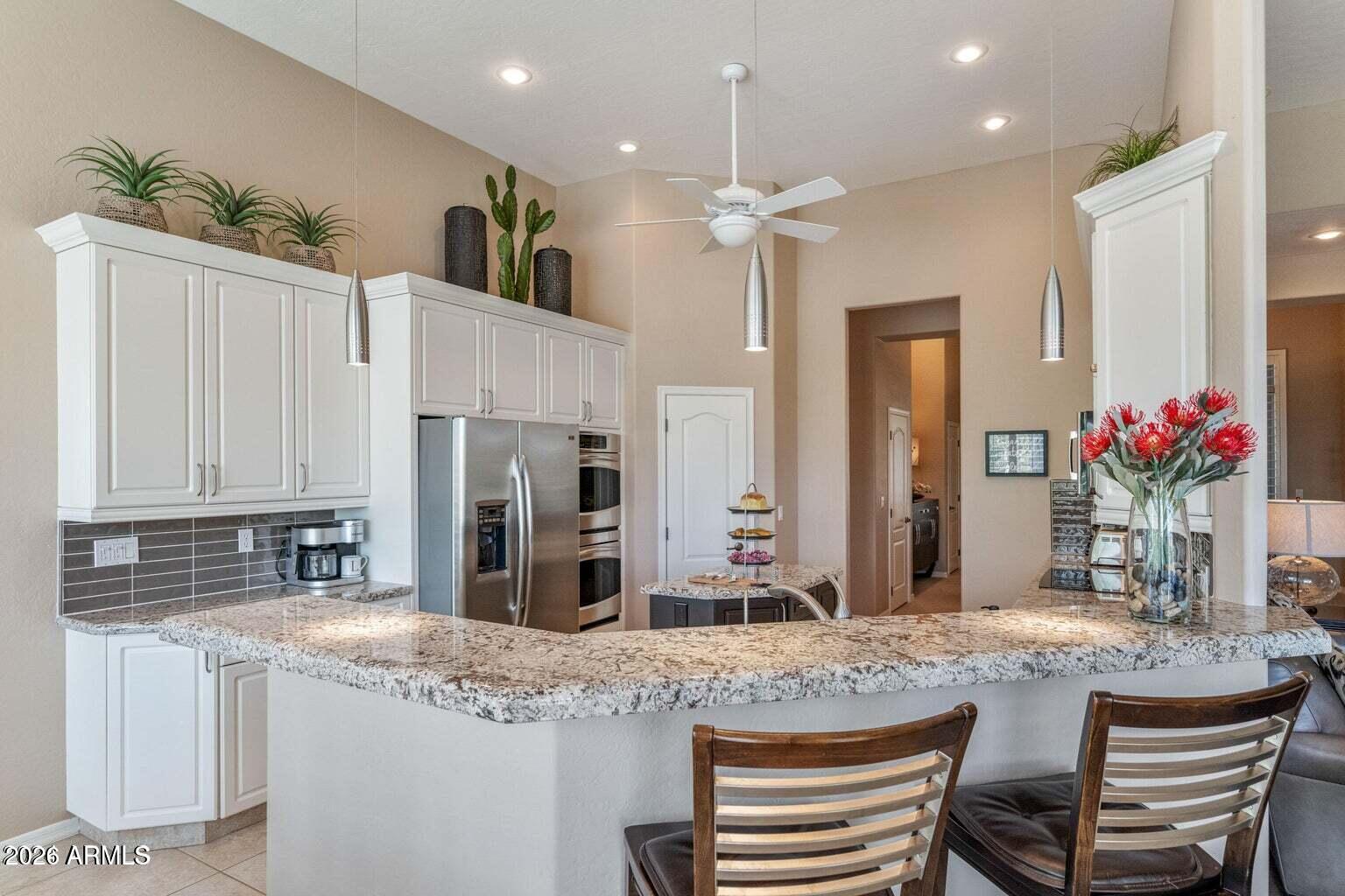 26601 North Aguila Road Rio Verde, AZ 85263 - Photo 12 of 45 a kitchen with kitchen island granite countertop a sink and white cabinets