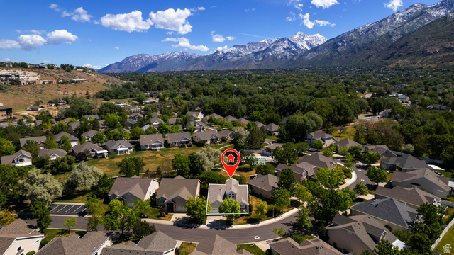 1417 Blacksmith Lane Draper, UT 84020 - Photo 52 of 57 Aerial view showcasing a residential neighborhood with varied architectural styles and mature trees, set against a backdrop of snow-capped mountains and expansive green hills
