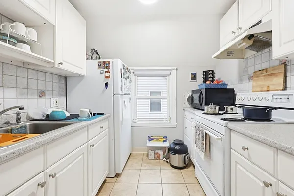 a kitchen with a sink dishwasher stove and white cabinets