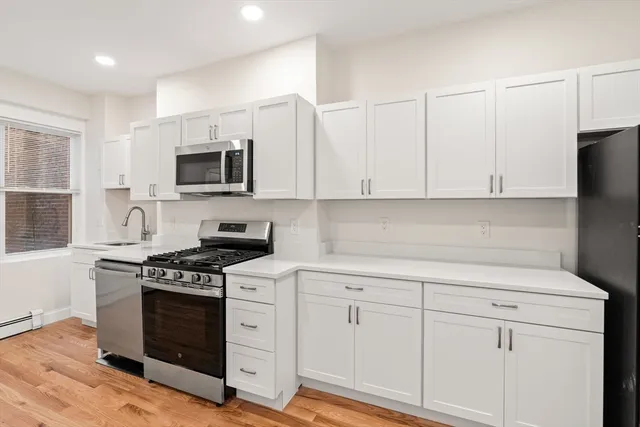 a kitchen with white cabinets and appliances
