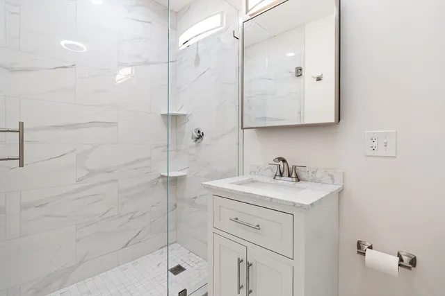 a bathroom with a sink vanity granite and shower