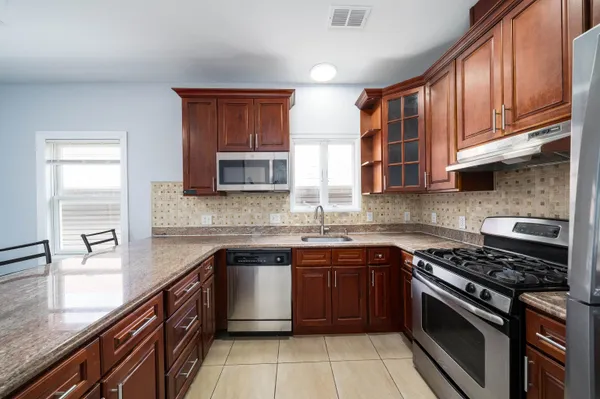 a kitchen with stainless steel appliances granite countertop wooden cabinets stove top oven and sink