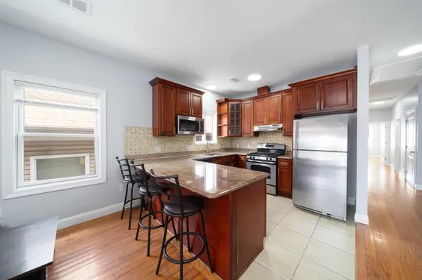 a kitchen with granite countertop stainless steel appliances a refrigerator a stove a sink a dining table and chairs