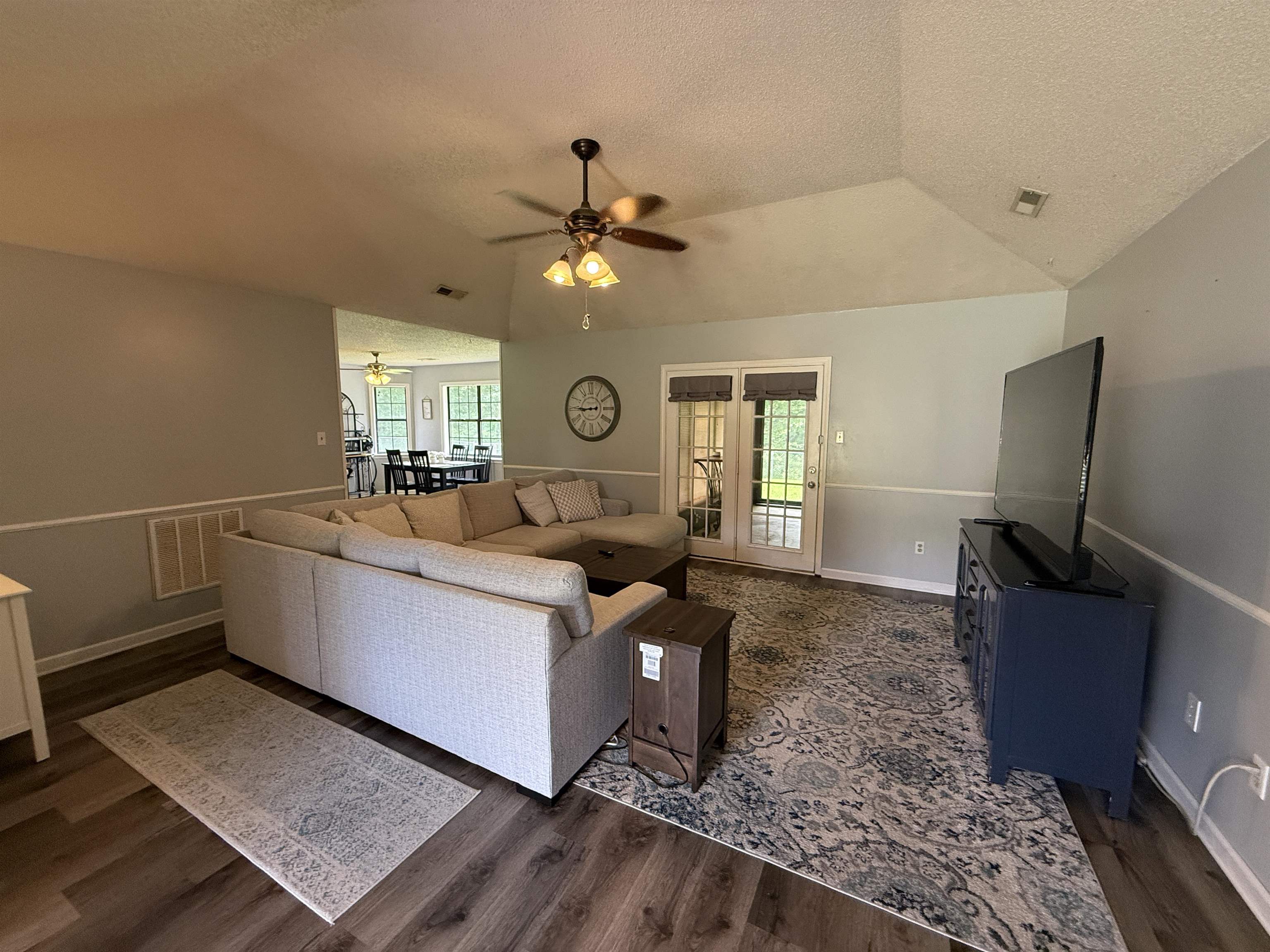 185 Mignon Road Atoka, TN 38004 - Photo 13 of 34 Spacious living area featuring vaulted ceilings, wood-finish flooring, two-tone wall paint with wainscoting, and French doors