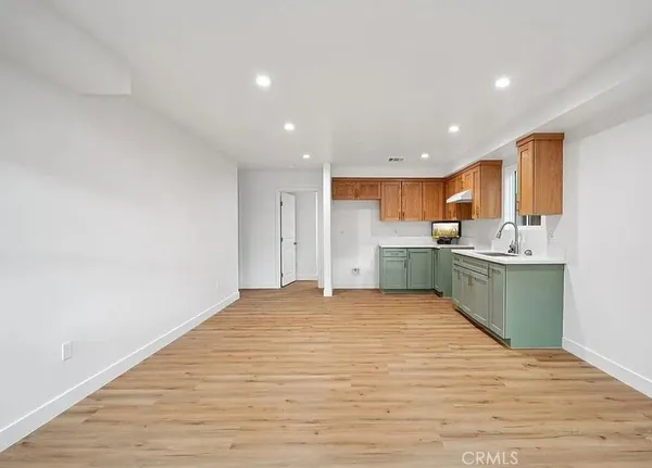 a view of kitchen with kitchen island a sink wooden floor and a refrigerator