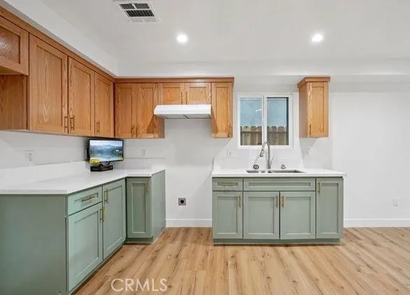 a kitchen with a sink cabinets and wooden floor