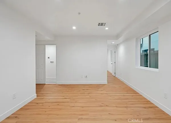 a view of an empty room with wooden floor and a window
