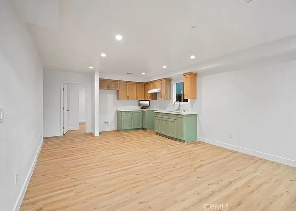 a view of kitchen with kitchen island a sink dishwasher and a refrigerator with wooden floor
