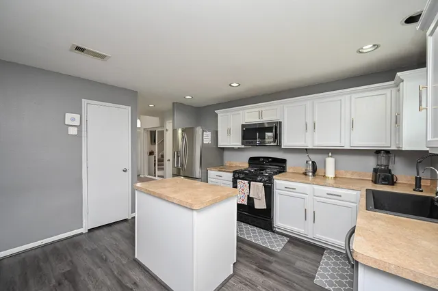 a kitchen with a sink a stove a refrigerator and white cabinets