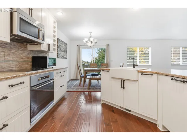 a open kitchen with granite countertop a stove top oven a sink dishwasher and a fireplace with wooden floor