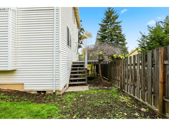 a view of a backyard with plants and wooden fence