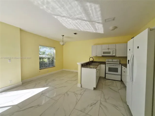 a kitchen with a refrigerator a stove top oven and cabinets
