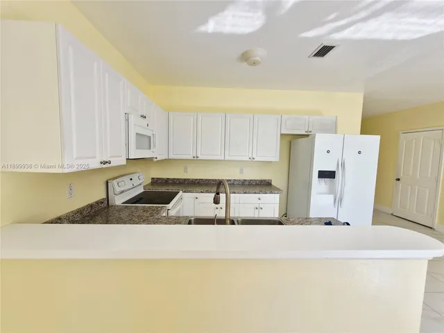a kitchen with granite countertop a sink a stove and a refrigerator