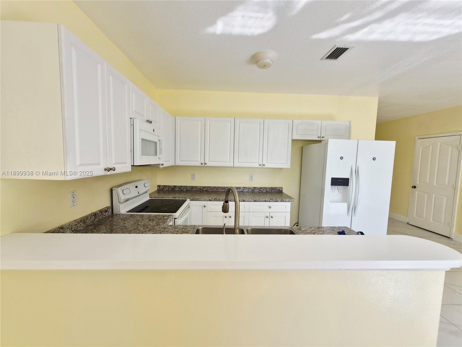 1209 Northwest 27th Avenue Pompano Beach, FL 33069 - Photo 7 of 22 a kitchen with granite countertop a sink a stove and a refrigerator